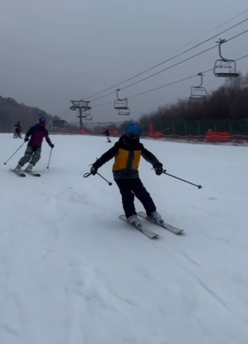 Beginner ski lesson AFTER scene with a student practicing balance and linked turns while an instructor follows